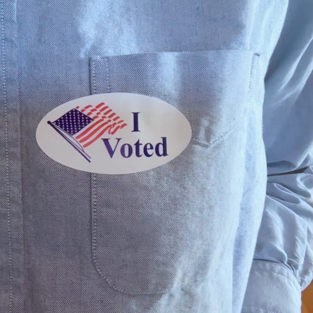 A sticker saying "I voted" on a blue shirt.